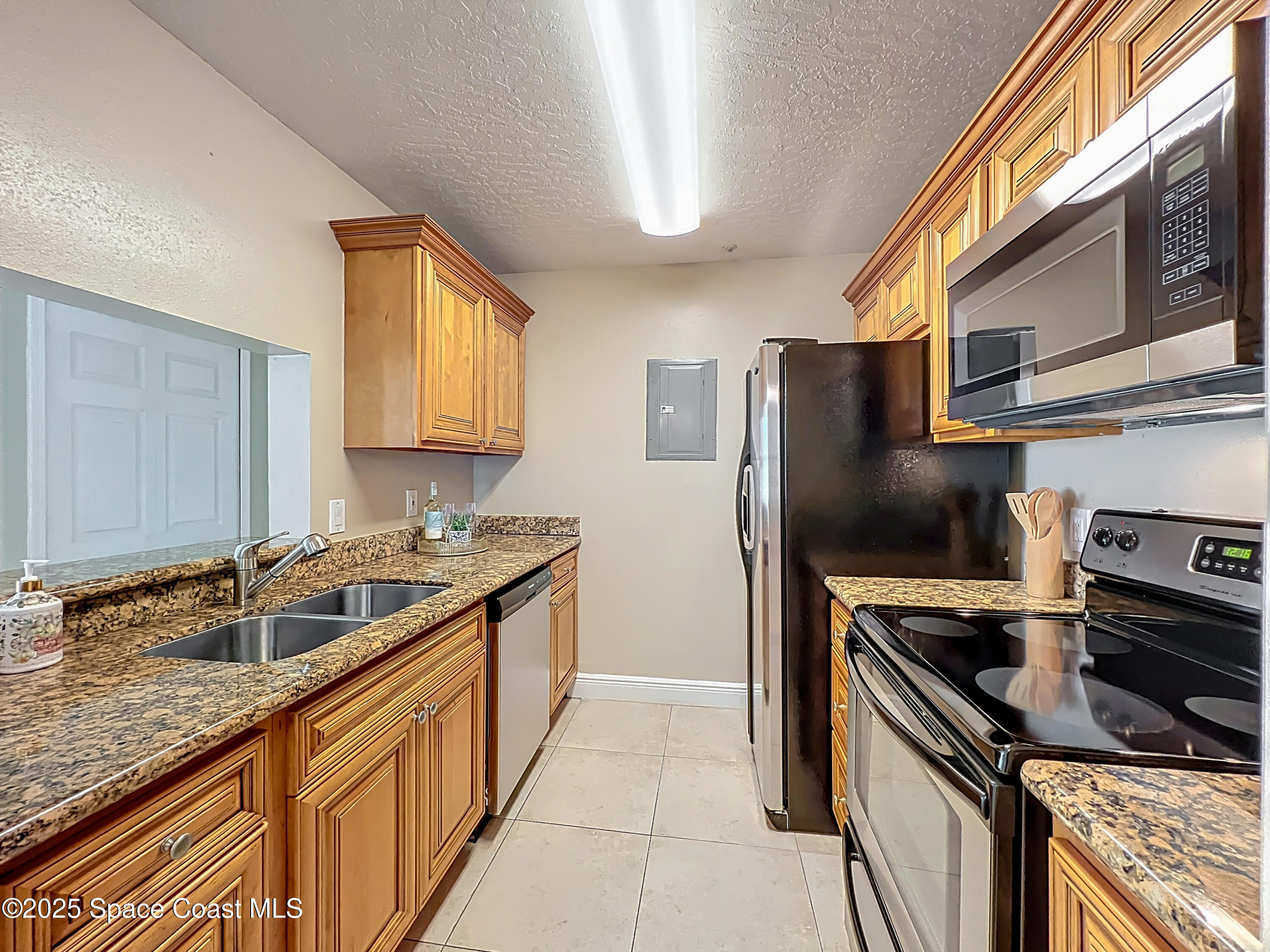 7667 North Wickham Road, Unit 410 Melbourne, FL 32940 - Photo 7 of 37 a kitchen with granite countertop a sink and stainless steel appliances