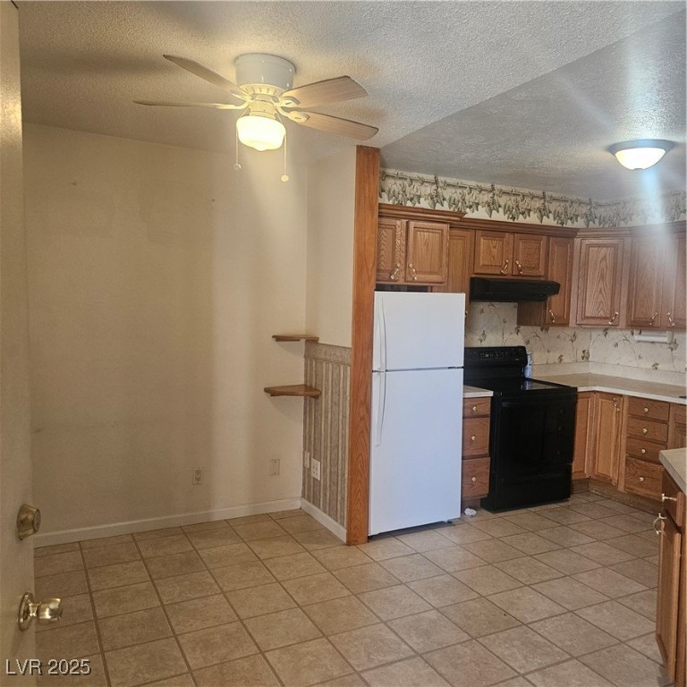 350 East Desert Inn Road, Unit C203 Las Vegas, NV 89109 - Photo 11 of 35 Kitchen featuring a textured ceiling, fridge, brown cabinetry, range, and light countertops