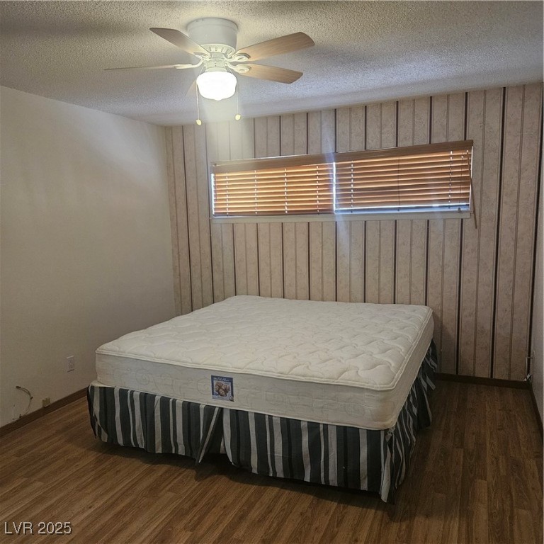 350 East Desert Inn Road, Unit C203 Las Vegas, NV 89109 - Photo 13 of 35 Bedroom with a textured ceiling, wooden walls, ceiling fan, and dark wood-style flooring