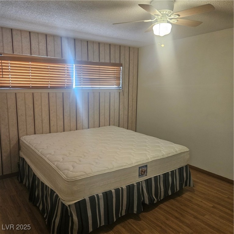 350 East Desert Inn Road, Unit C203 Las Vegas, NV 89109 - Photo 14 of 35 Bedroom featuring a textured ceiling, wood walls, dark wood-style flooring, and a ceiling fan