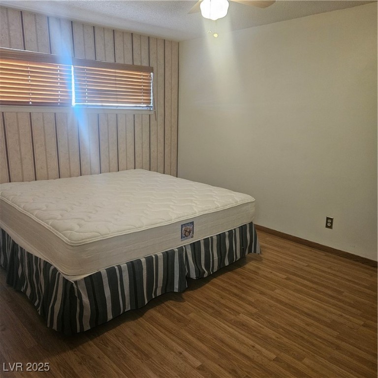 350 East Desert Inn Road, Unit C203 Las Vegas, NV 89109 - Photo 21 of 35 Bedroom featuring wooden walls, dark wood-type flooring, a ceiling fan, and a textured ceiling