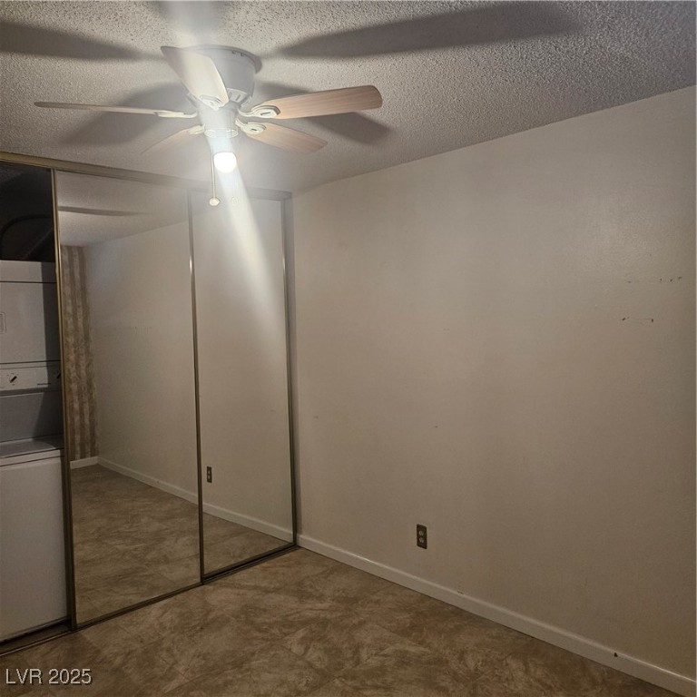 350 East Desert Inn Road, Unit C203 Las Vegas, NV 89109 - Photo 24 of 35 Unfurnished bedroom with a closet, a textured ceiling, a ceiling fan, and stacked washer / dryer