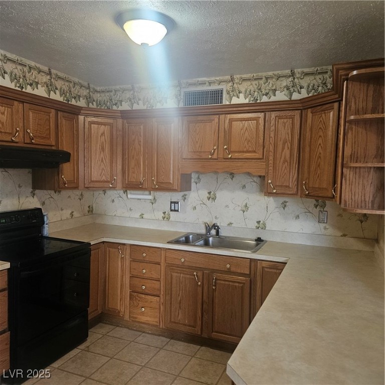 350 East Desert Inn Road, Unit C203 Las Vegas, NV 89109 - Photo 5 of 35 Kitchen with wallpapered walls, range, a textured ceiling, brown cabinets, and light countertops