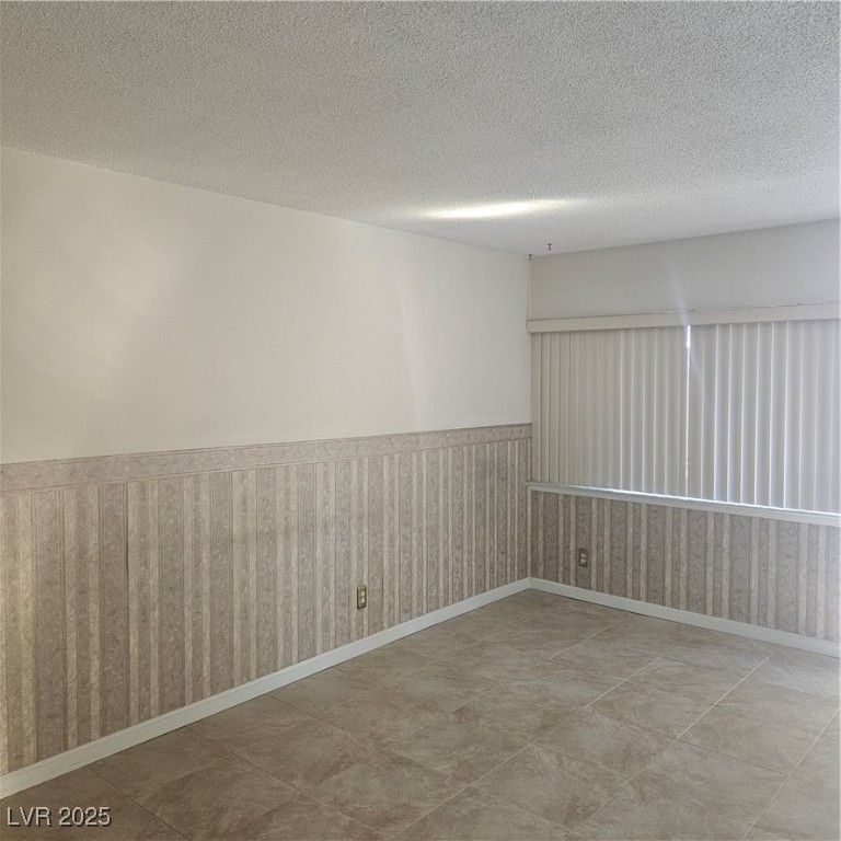 350 East Desert Inn Road, Unit C203 Las Vegas, NV 89109 - Photo 8 of 35 Unfurnished room with wainscoting, a textured ceiling, wallpapered walls, and light tile patterned floors