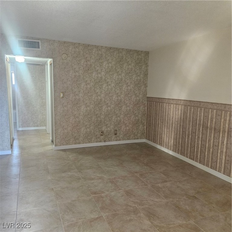 350 East Desert Inn Road, Unit C203 Las Vegas, NV 89109 - Photo 10 of 35 Spare room with a textured ceiling, a wainscoted wall, and wallpapered walls