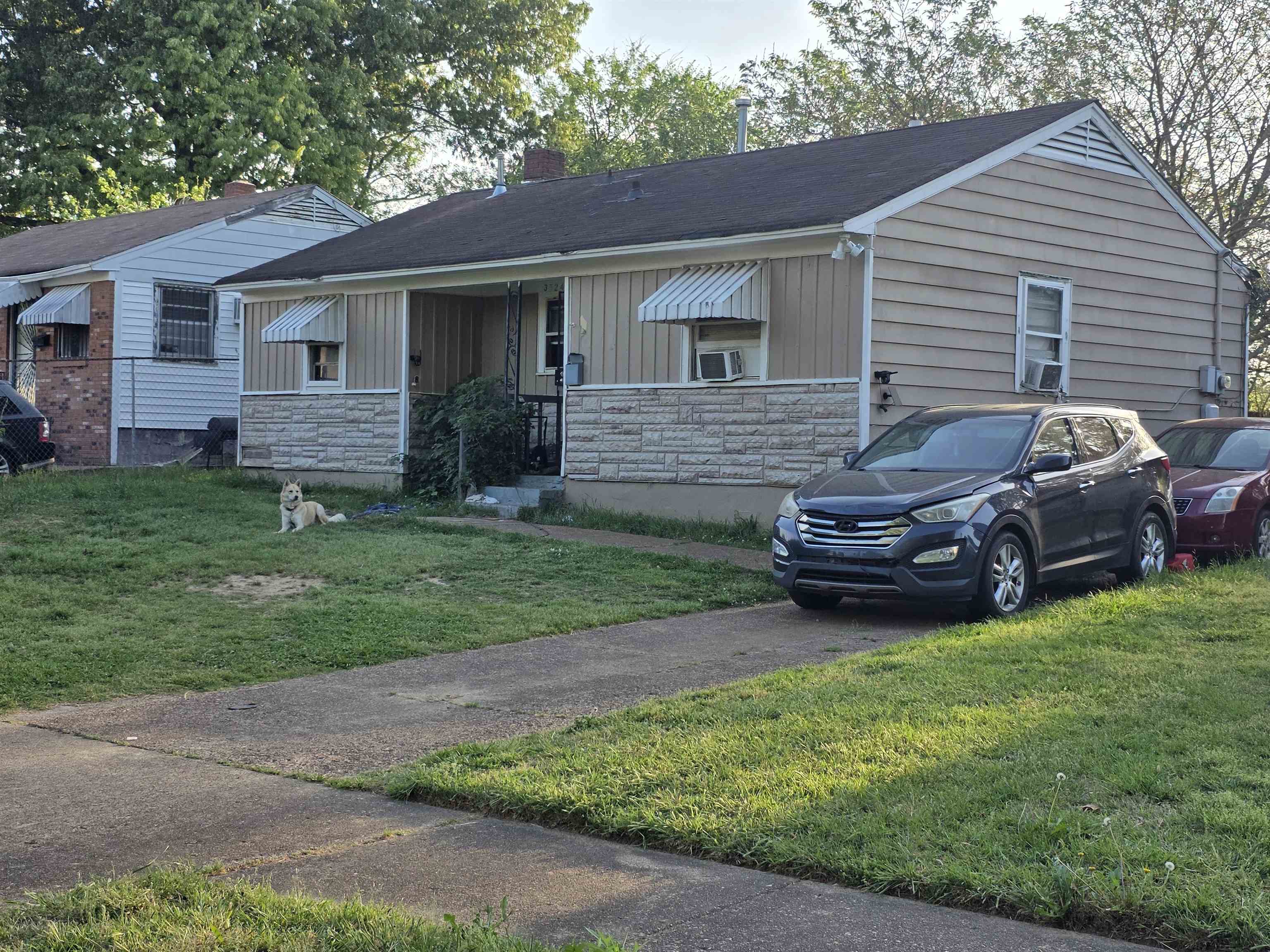 View of front of home with board and batten siding, stone siding, a front lawn, and a porch