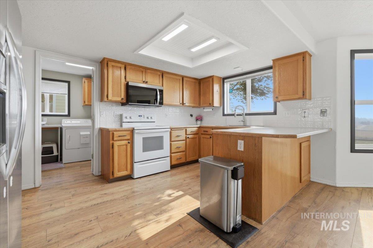 24440 Kenridge Road Caldwell, ID 83607 - Photo 13 of 48 Kitchen featuring wood-finish flooring, shaker-style wood cabinetry, white subway tile backsplash, and a white countertop