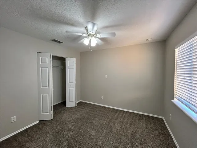 an empty room with windows and fan