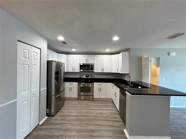 a view of a kitchen with a sink dishwasher a refrigerator with wooden floor and a workspace