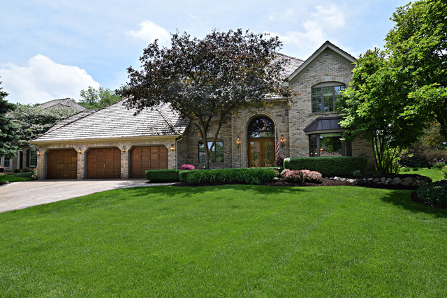 a front view of a house with a garden and trees