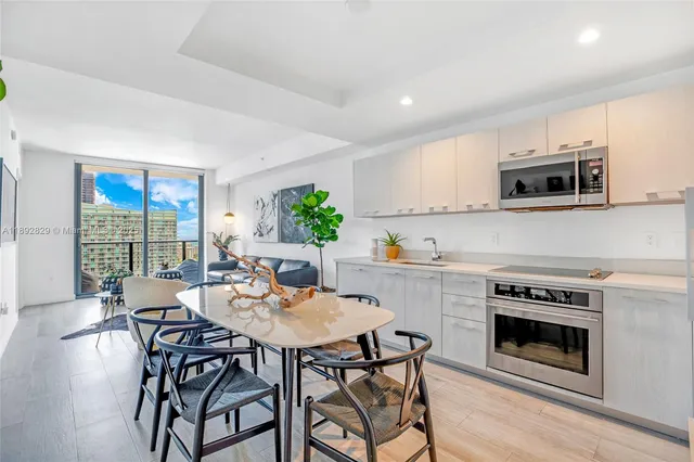 a kitchen with stainless steel appliances a stove a sink a microwave a dining table and chairs