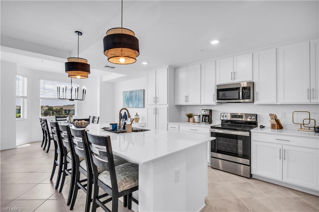 43989 Boardwalk Loop, Unit 2032 Punta Gorda, FL 33982 - Photo 2 of 14 a kitchen with stainless steel appliances a dining table chairs stove and white cabinets