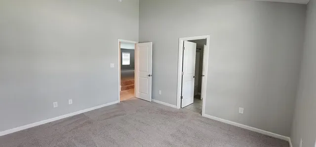 an empty room with a ceiling fan and carpet