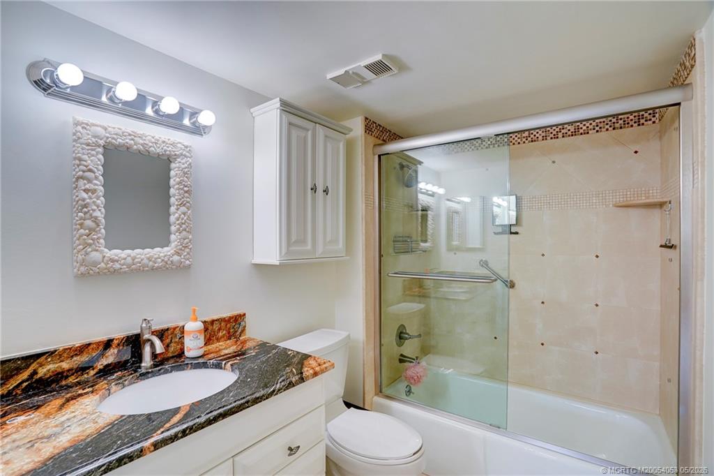 10 Northeast Plantation Road, Unit 101 Jensen Beach, FL 34957 - Photo 44 of 53 a bathroom with a granite countertop sink toilet a shower and a mirror