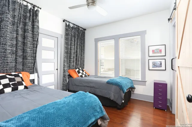 a bedroom with two beds and a large mirror next to a window