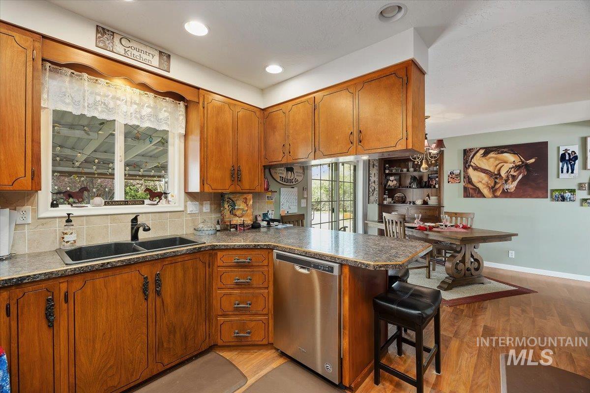 1301 A Street Rupert, ID 83350 - Photo 15 of 45 Kitchen featuring wood finish cabinets, a peninsula, dishwasher, decorative backsplash, and dark countertops