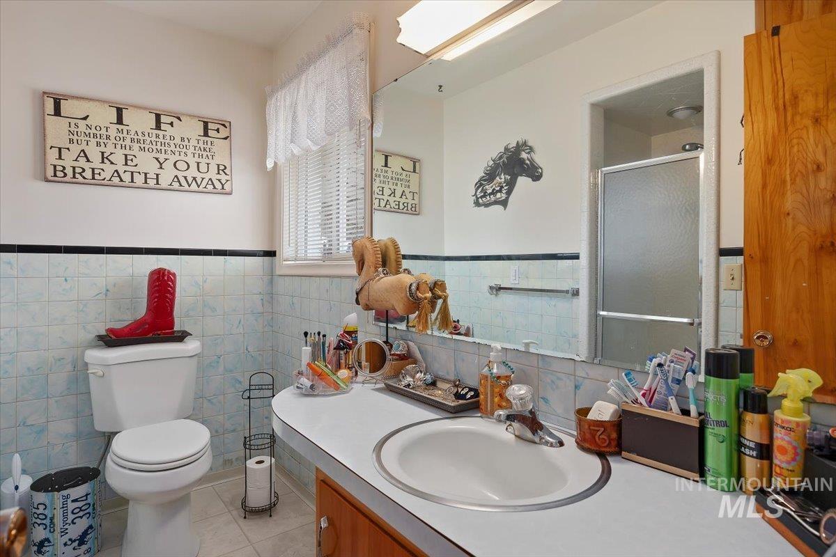 1301 A Street Rupert, ID 83350 - Photo 23 of 45 Bathroom featuring vanity, wainscoting, a stall shower, tile walls, and light tile patterned flooring