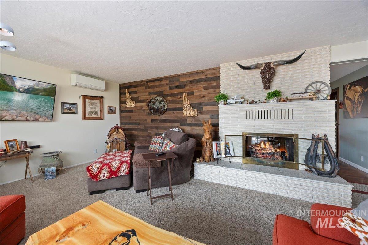1301 A Street Rupert, ID 83350 - Photo 6 of 45 Living area with wood walls, a fireplace, a textured ceiling, and carpet flooring