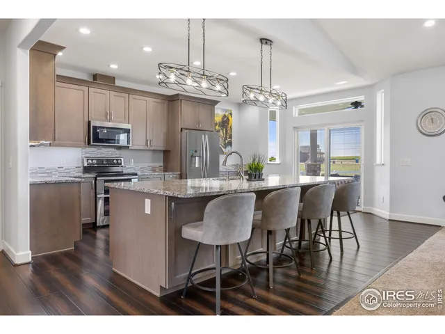 a kitchen with granite countertop a stove a refrigerator and a oven with wooden floor