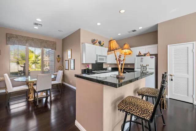 a kitchen with stainless steel appliances granite countertop a stove top oven a dining table and chairs with wooden floor