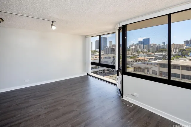a view of a big room with wooden floor and windows