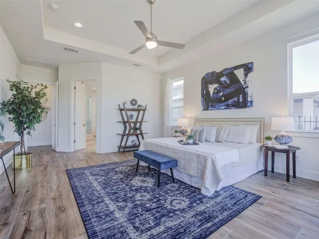 a spacious bedroom with a large bed a rug and potted plant