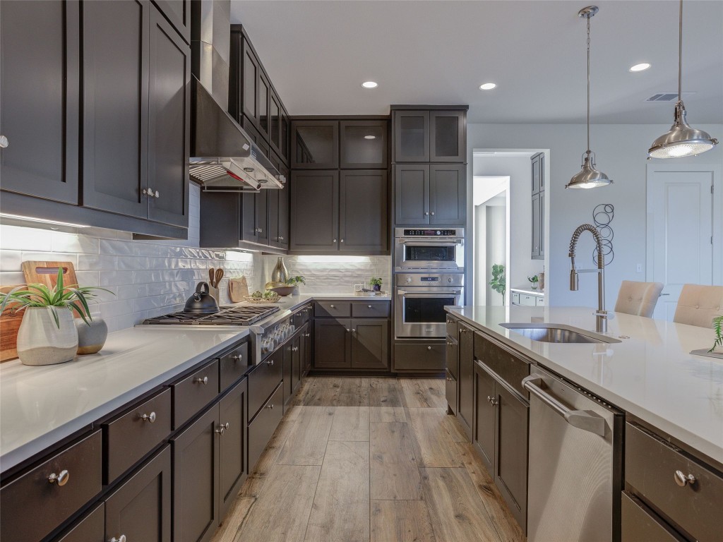 345 Two Creeks Lane Austin, TX 78737 - Photo 8 of 40 a kitchen with stainless steel appliances granite countertop a sink a stove and a wooden floors