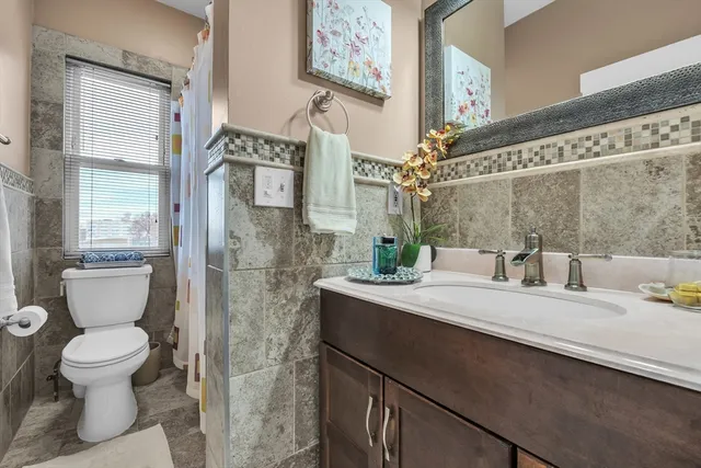 a bathroom with a granite countertop sink mirror vanity and toilet