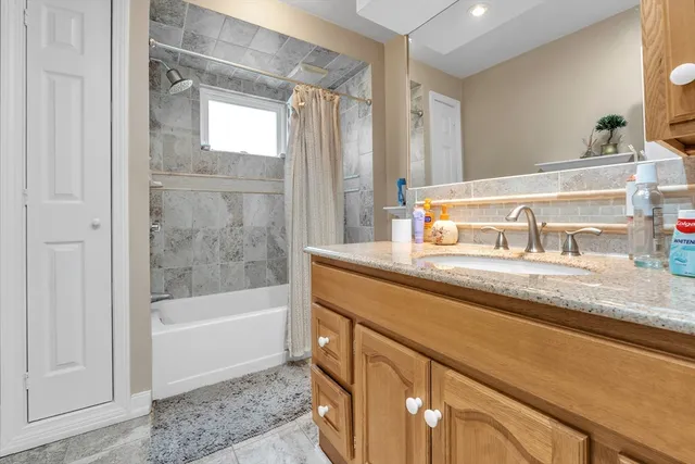 a bathroom with a granite countertop sink a mirror and a bathtub