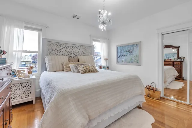 a bedroom with a bed a chandelier and a dresser