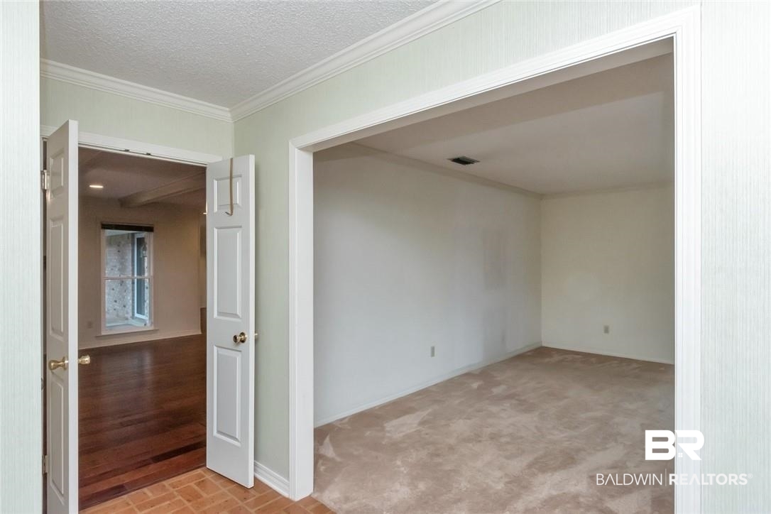 6109 Timberly Road North Mobile, AL 36609 - Photo 10 of 26 Unfurnished room with a textured ceiling, crown molding, and light colored carpet