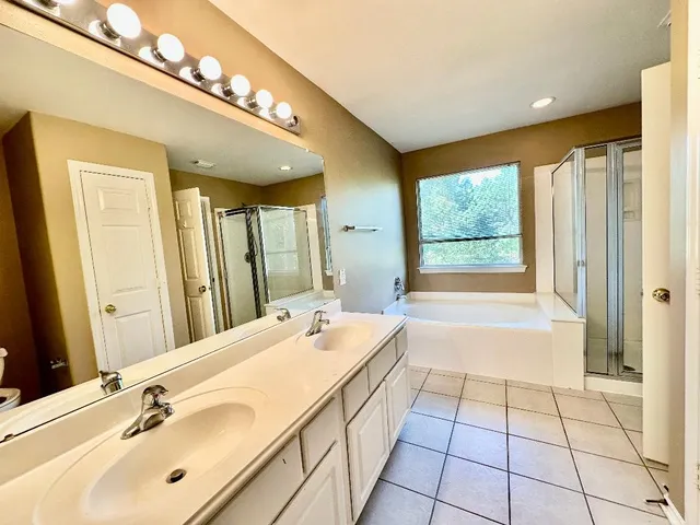 a spacious bathroom with a double vanity sink a large mirror and a bathtub