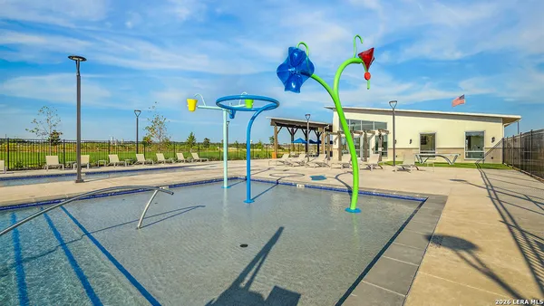 a view of swimming pool with outdoor seating and trees in the background