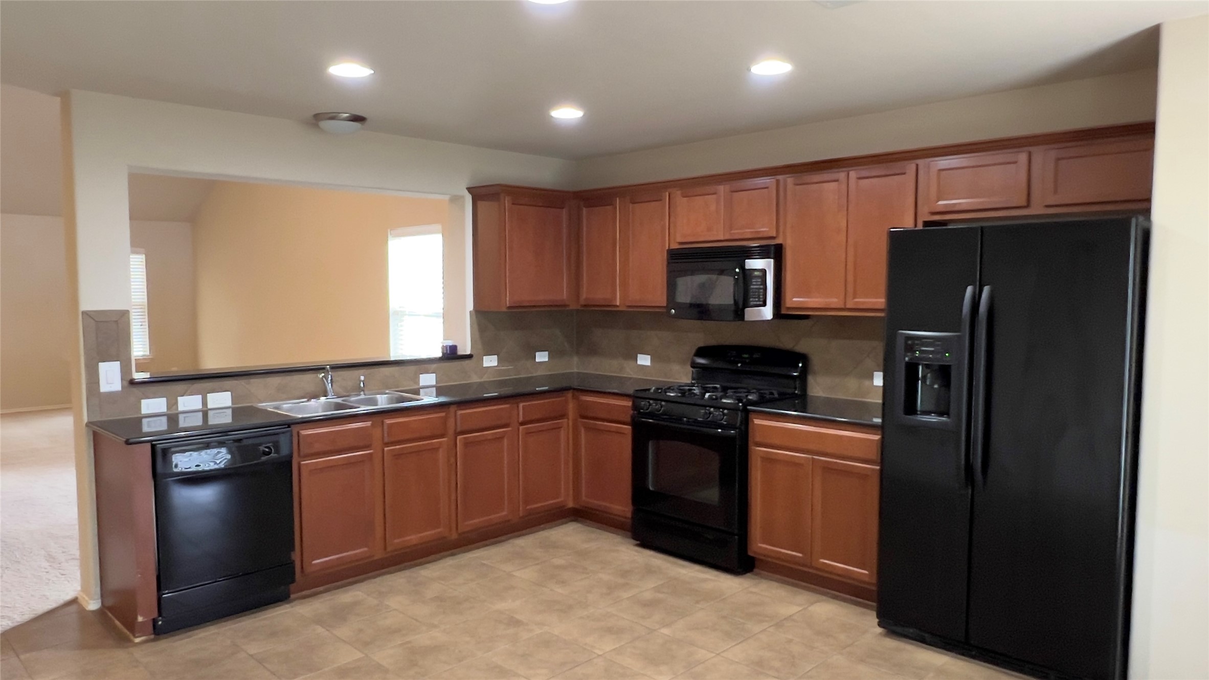 357 Nottingham Loop Kyle, TX 78640 - Photo 2 of 22 Rich wood cabinetry paired with dark countertops defines this functional kitchen layout.