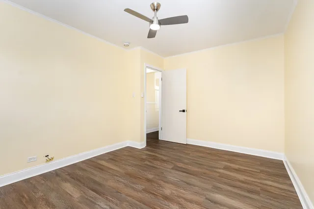 an empty room with wooden floor and ceiling fan