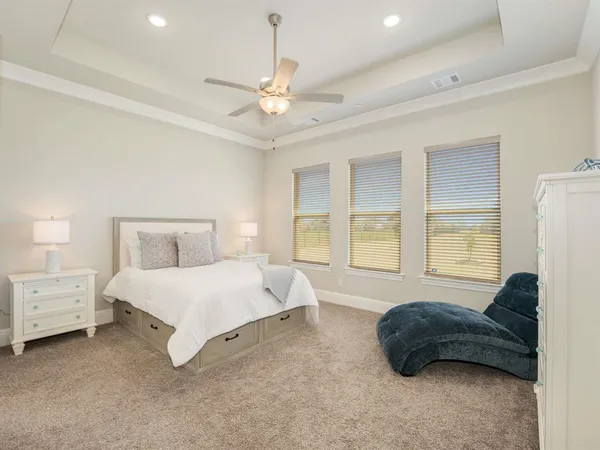 a spacious bedroom with a bed a chandelier and a couch