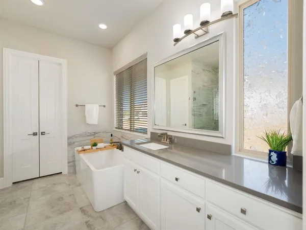 a bathroom with a granite countertop sink a large mirror a bathtub and shower