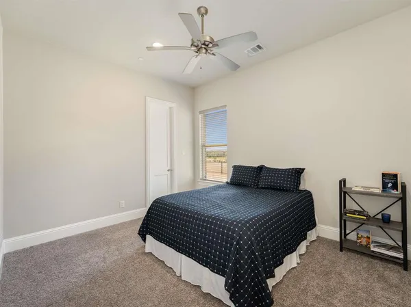 a bedroom with a bed a chair and a potted plant on a dresser