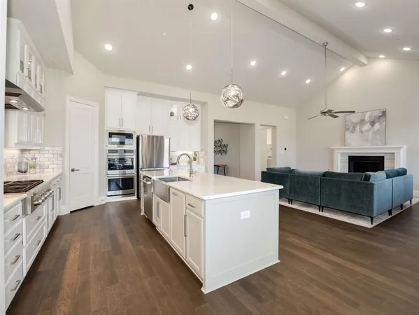 a large kitchen with stainless steel appliances a large counter top a stove and a sink