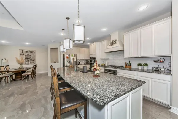 a kitchen with kitchen island granite countertop a table chairs sink and cabinets