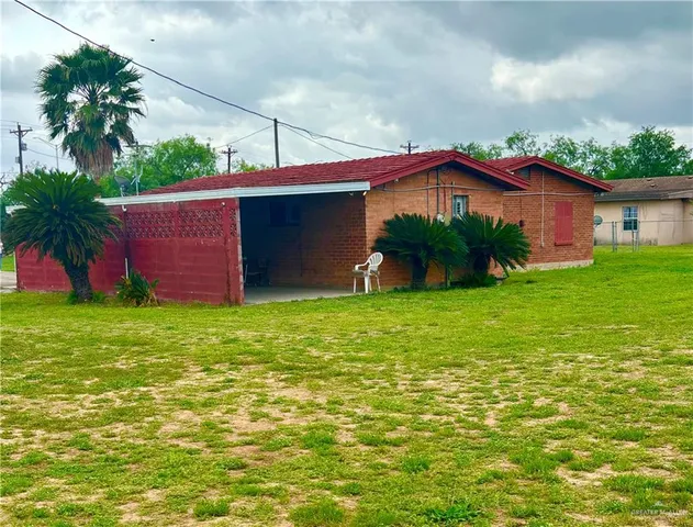 a view of a yard in front of a house with plants and large tree