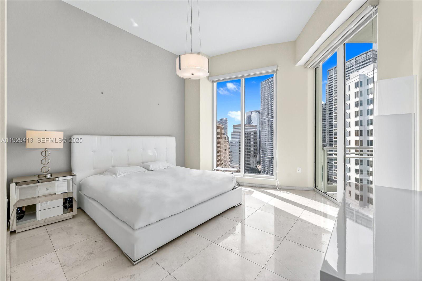 900 Brickell Key Boulevard, Unit 2605 Miami, FL 33131 - Photo 11 of 43 a bedroom with a large bed and a chandelier