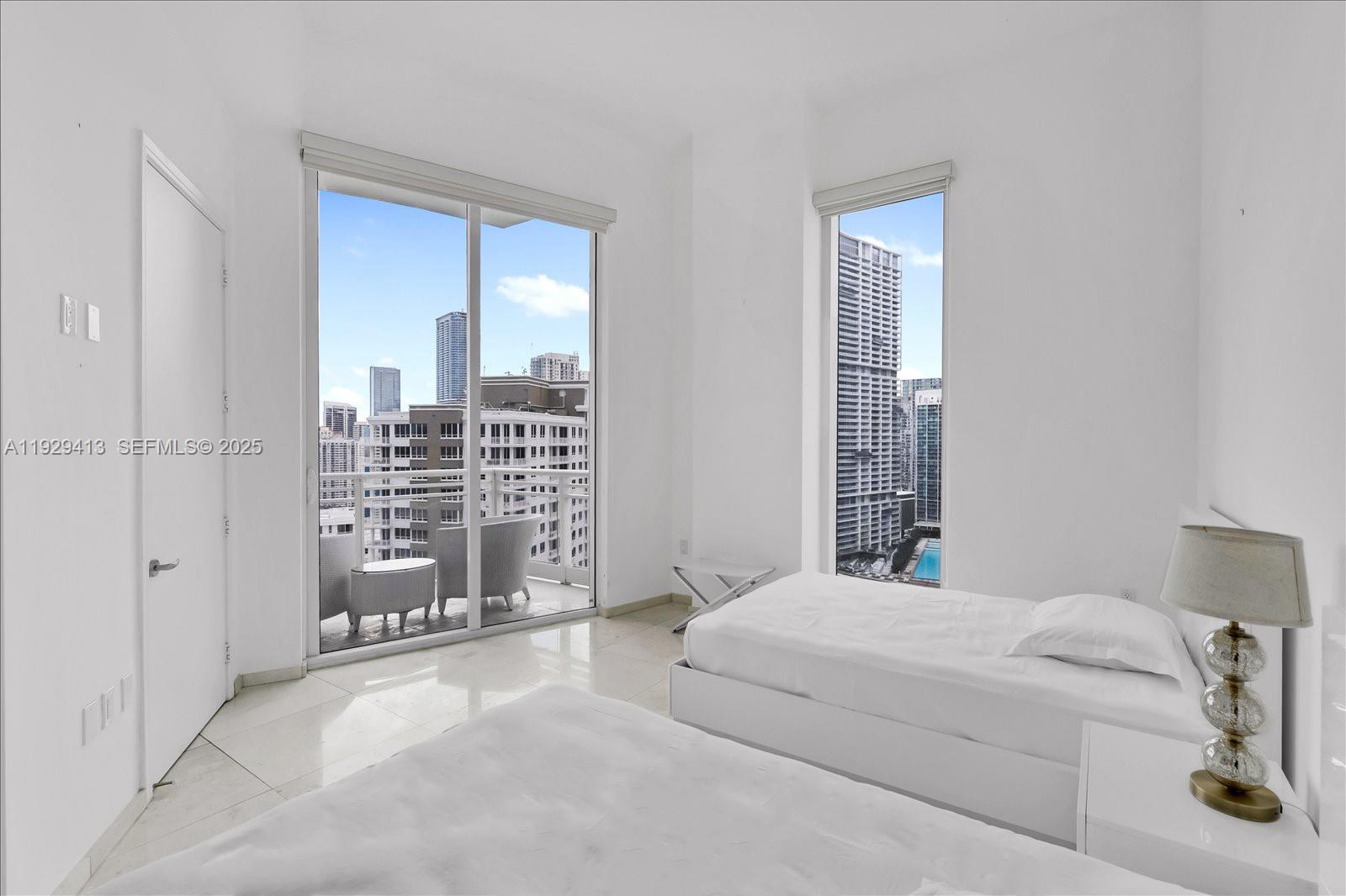 900 Brickell Key Boulevard, Unit 2605 Miami, FL 33131 - Photo 24 of 43 a bedroom with a large bed and a chandelier