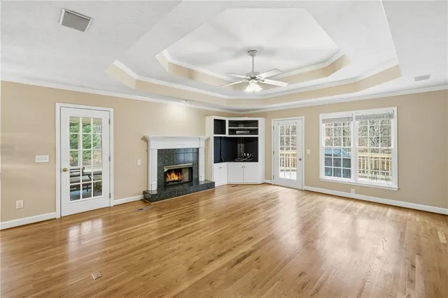 an empty room with wooden floor fireplace and windows