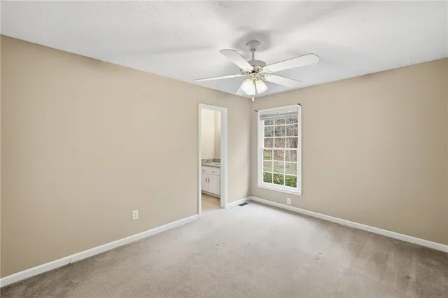 an empty room with chandelier fan and windows