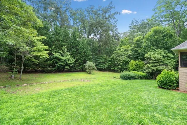 a view of a house with a big yard plants and large trees