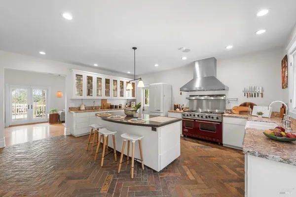 a kitchen with stainless steel appliances granite countertop a stove a sink a refrigerator and chairs