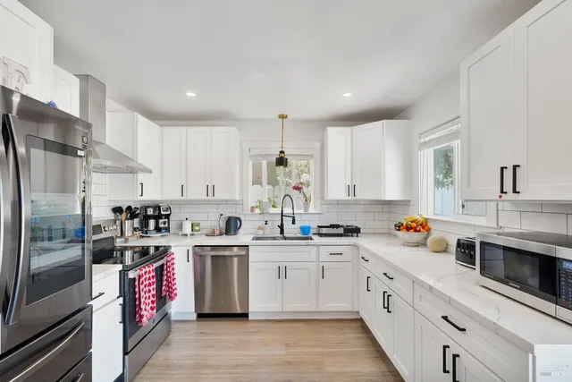 a kitchen with stainless steel appliances granite countertop a sink stove refrigerator and cabinets