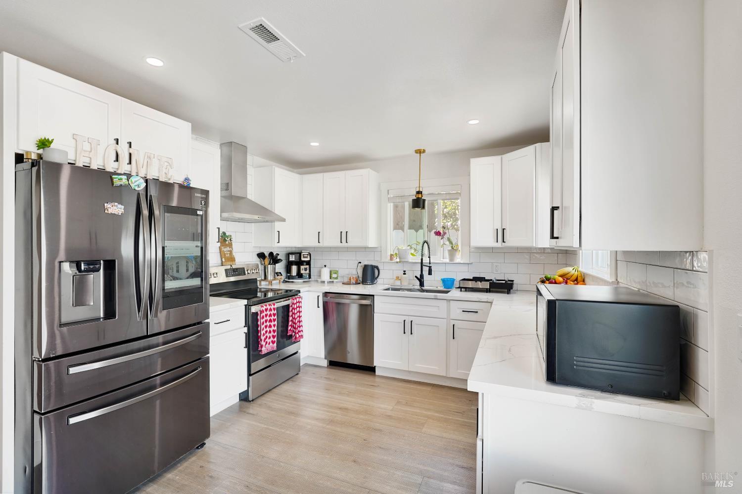 451 37th Street Richmond, CA 94805 - Photo 3 of 36 a kitchen with stainless steel appliances kitchen island granite countertop a refrigerator oven a sink dishwasher and white cabinets with wooden floor