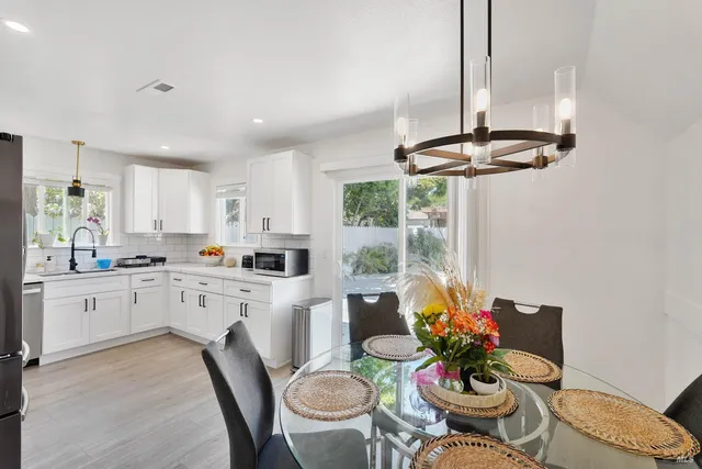 a kitchen with stainless steel appliances a dining table chairs and white cabinets